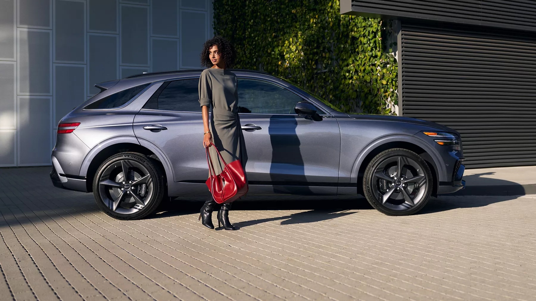 Woman standing next to a 2026 Genesis GV70 in Ceres Blue