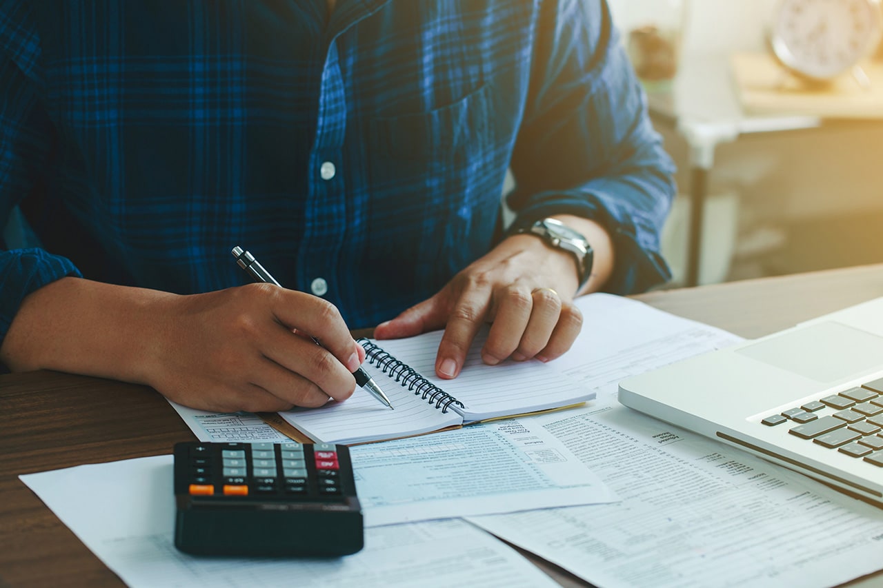 Man using calculator, paperwork, and note pad
