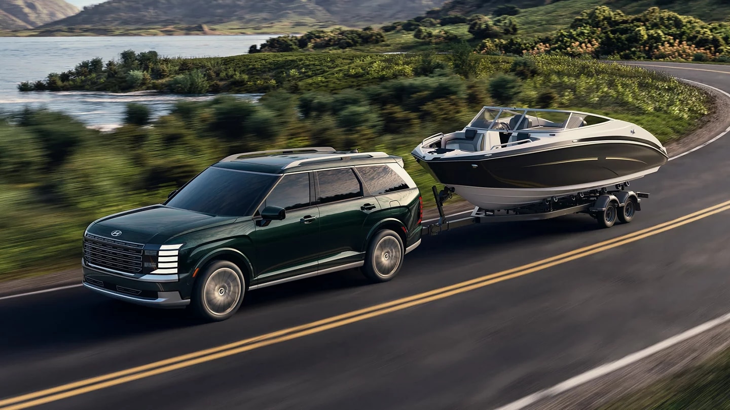 2026 Hyundai Palisade, in Robust Emerald Pearl finish, towing a speedboat.