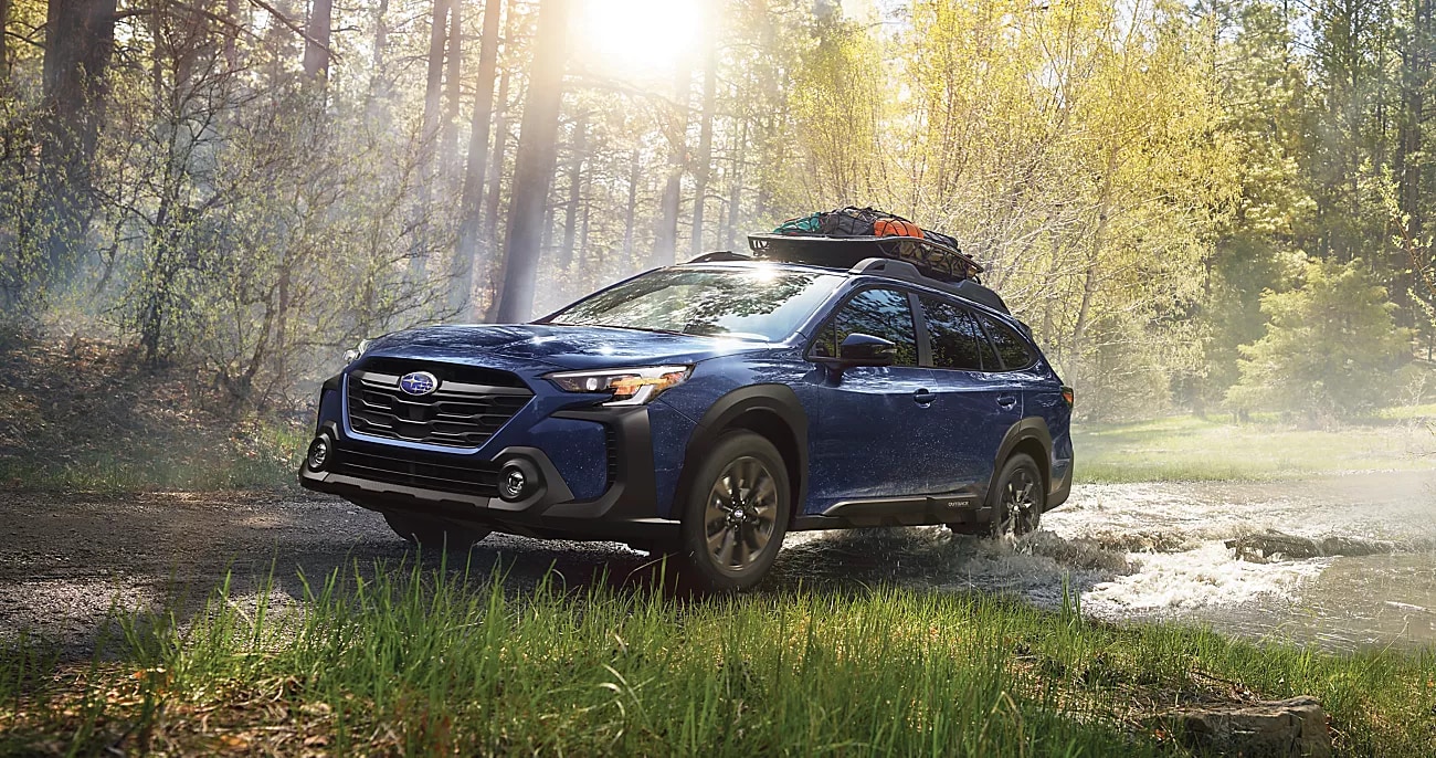Blue Subaru driving through a wooded outdoor setting