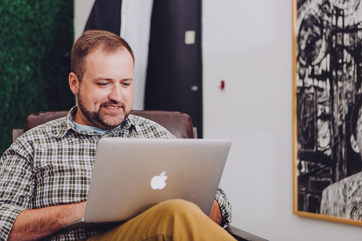 Happy man using a laptop to order OEM Volvo parts online