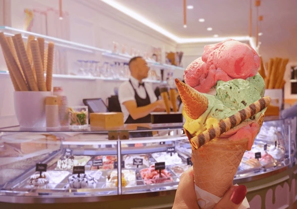 person holding up an ice cream cone at an ice cream shop