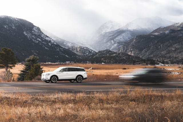 white lincoln aviator driving with mountains in background