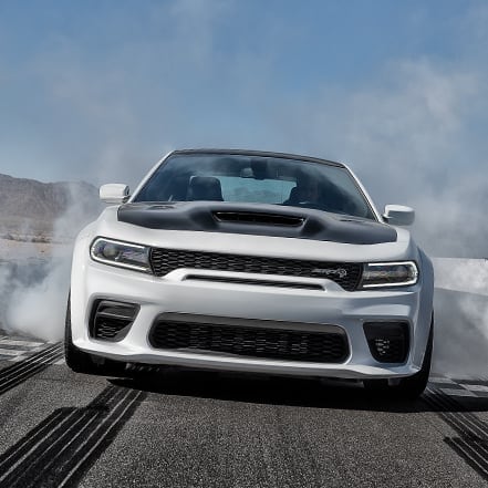 white Dodge Challenger spinning its wheels and burning rubber on a race track
