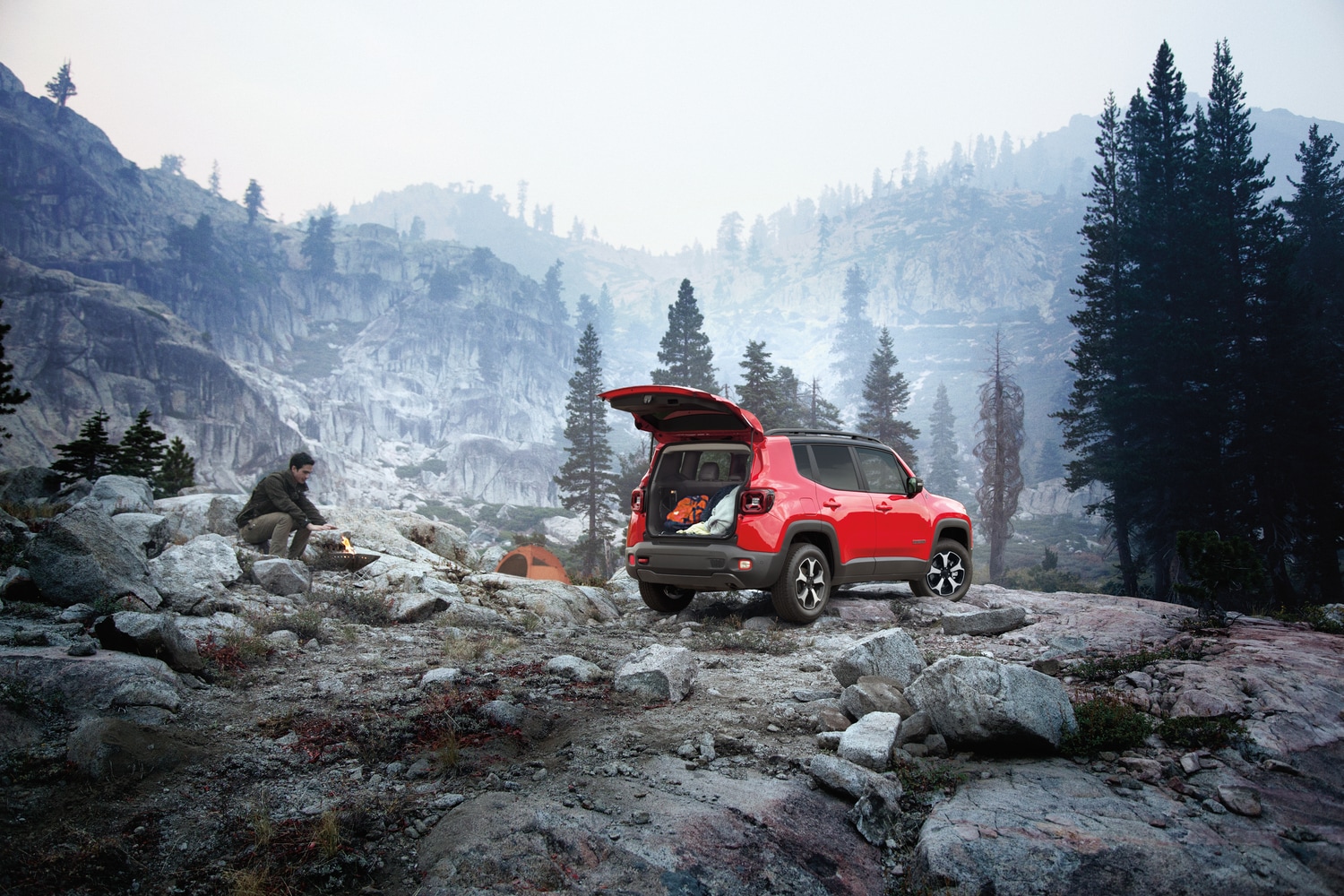 red Jeep Renegade SUV parked on a rocky hill with the trunk open