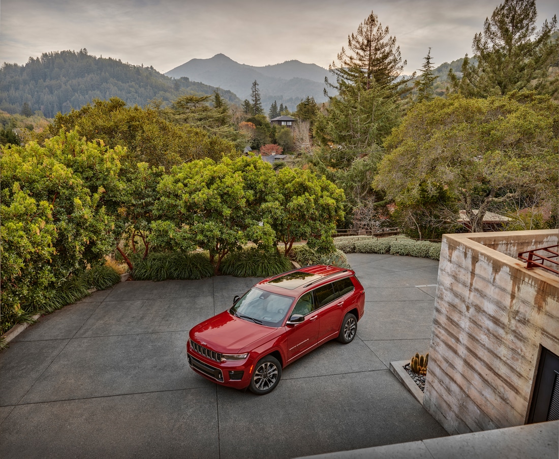red Jeep Grand Cherokee L third-row SUV parked in a long driveway, aerial view