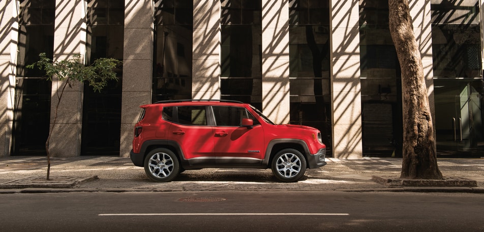 red Jeep Renegade parked in front of a cement city building