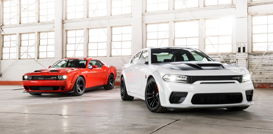 red and white Dodge Charger coupe and sedan lineup, parked inside an aircraft hanger
