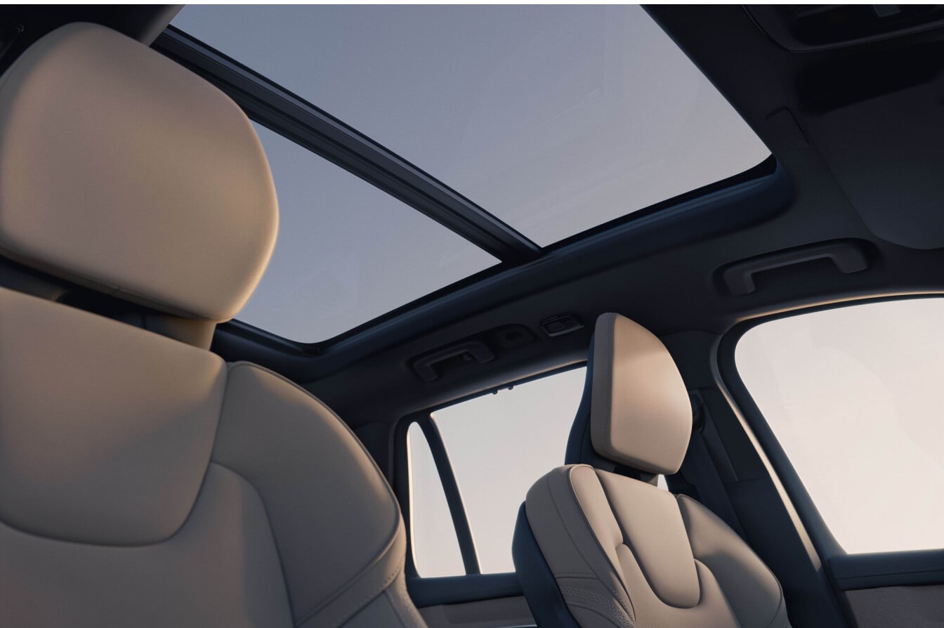 Interior view of a Volvo XC90 SUV showing beige leather seats and panoramic sunroof.