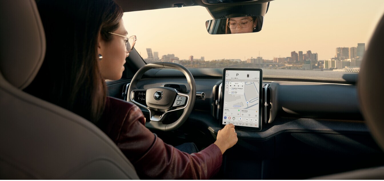 Driver perspective profile of a Volvo EX30 interior with a driver interacting with the central touchscreen.