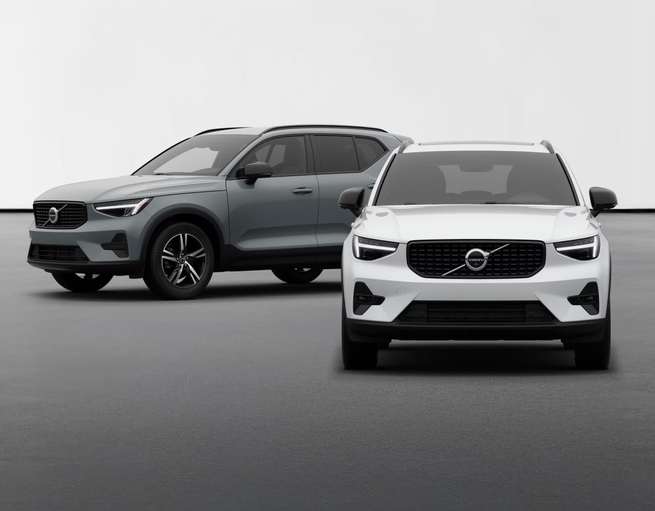 Two Volvo XC40 SUVs are showcased. The foreground is a white SUV with a sleek design, while a gray SUV is angled behind it, set against a plain backdrop.