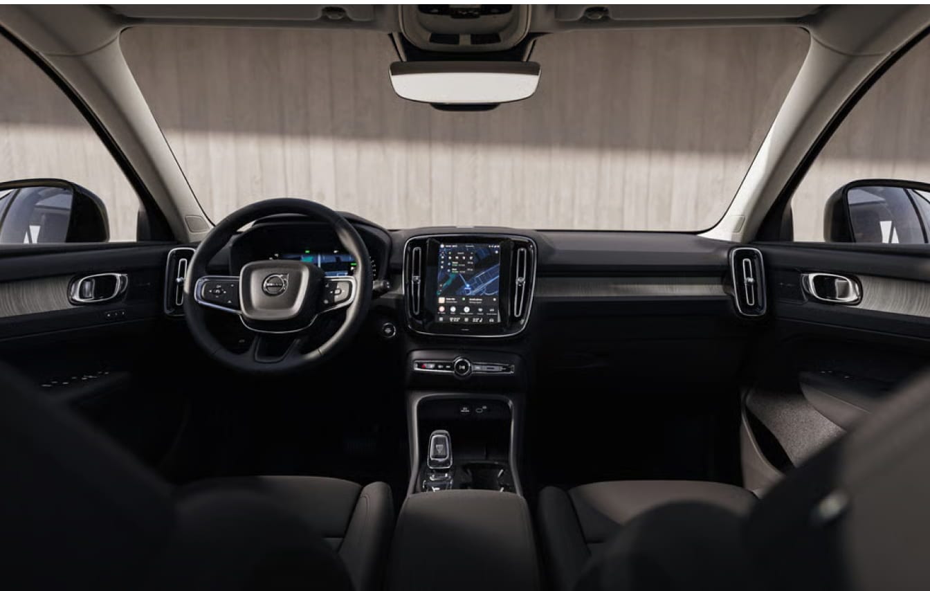 The image shows a Volvo XC40 car interior with a sleek dashboard, digital display, and leather seats.