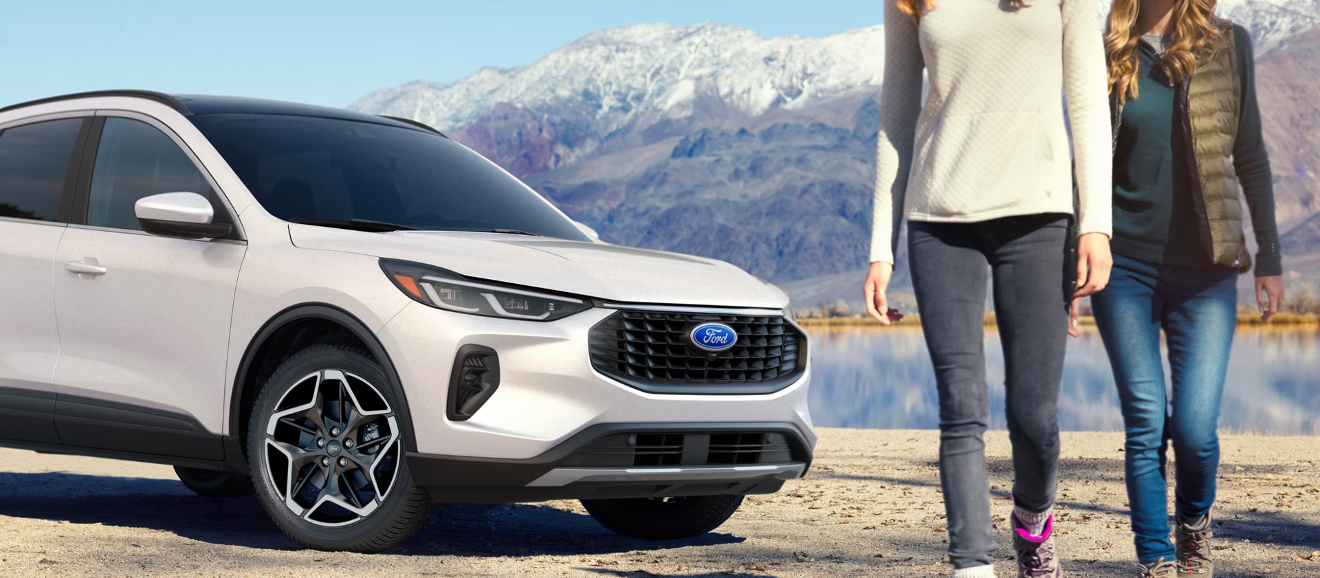 Couple with a white 2026 Ford Escape near mountains and a lake