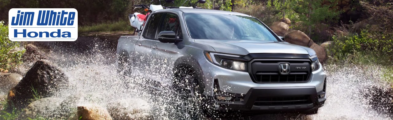 2025 Honda Ridgeline driving through Toledo streets, showing off its modern truck styling and LED headlights