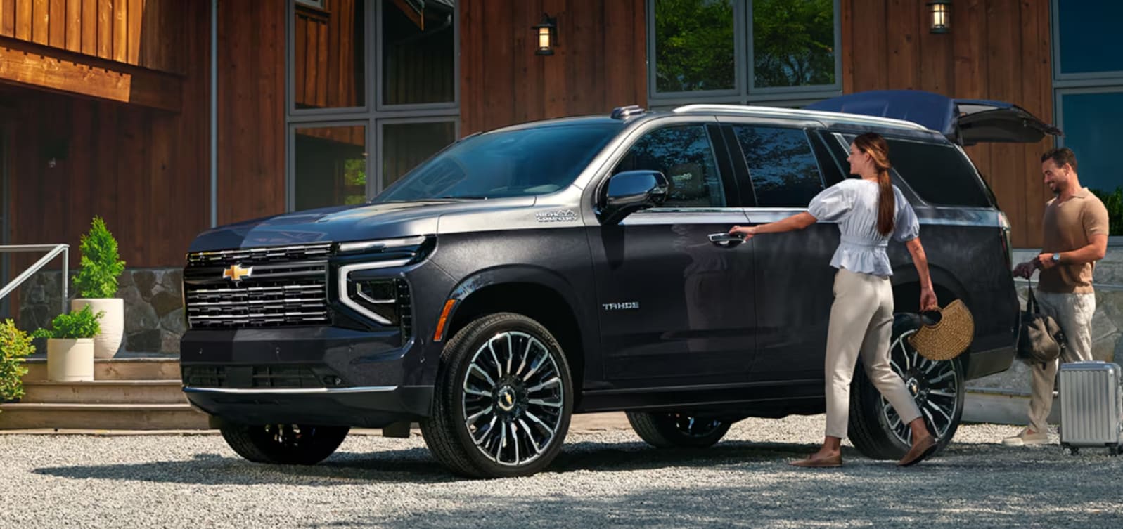 2026 Chevrolet Tahoe parked outside of cabin home with couple loading in.