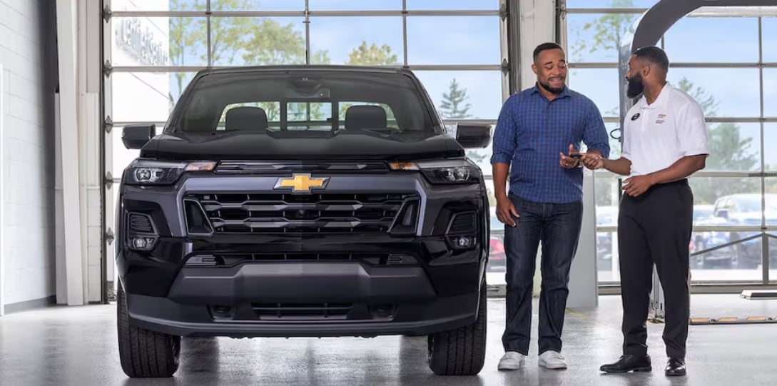 Chevrolet Sales Rep handing customer keys .