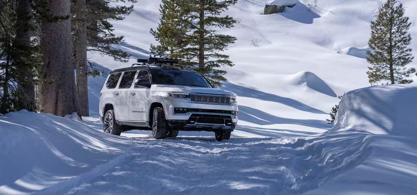 A white suv driving in the snow.
