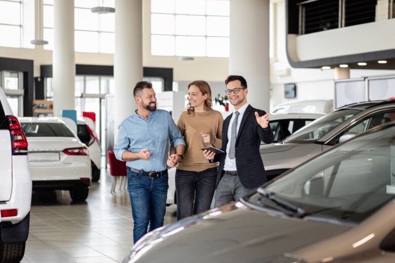 Salesmen showing a car to a couple