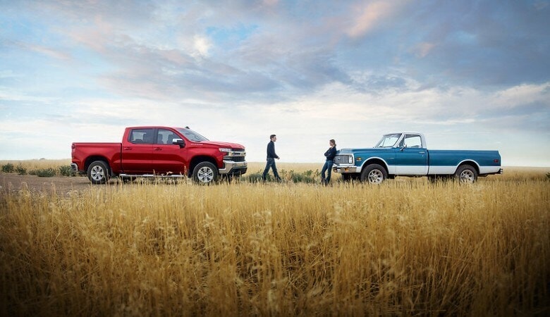A man and woman standing next to two Chevrolet Silverado 1500 trucks | Jones Chevrolet Humboldt | Humboldt, TN