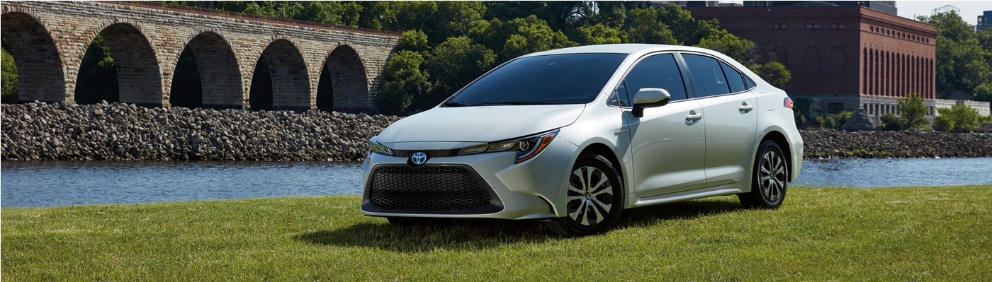 White Toyota Corolla Hybrid LE parked by a river