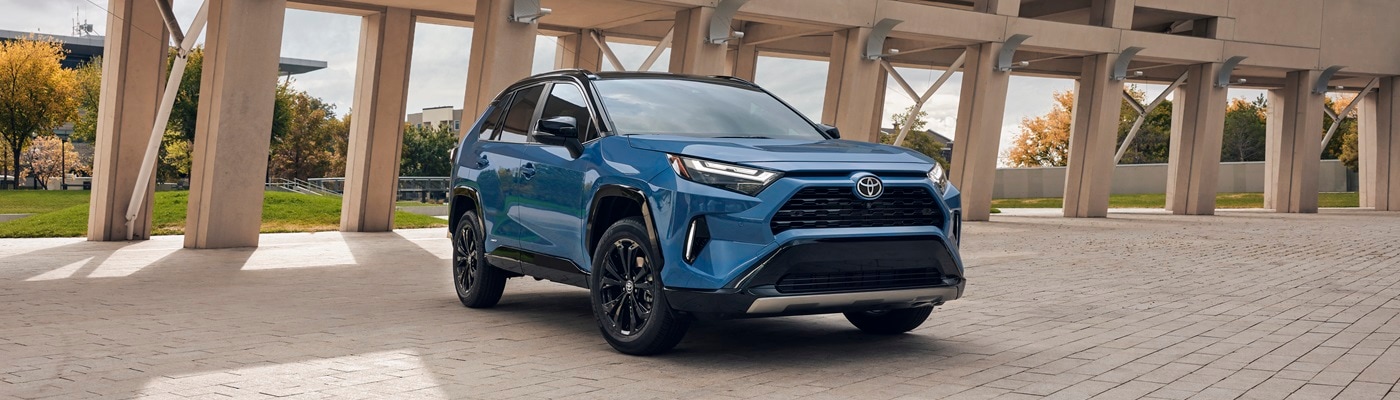 Blue Toyota RAV4 Hybrid XSE parked in front of a modern structure