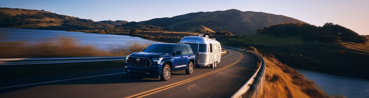 Blue Toyota Sequoia Platinum towing an airstream trailer on a road