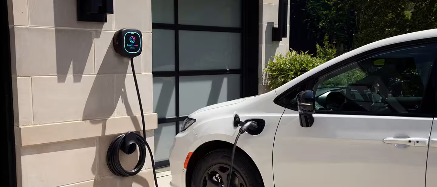 A white Plug-In Hybrid Pacifica being charged.