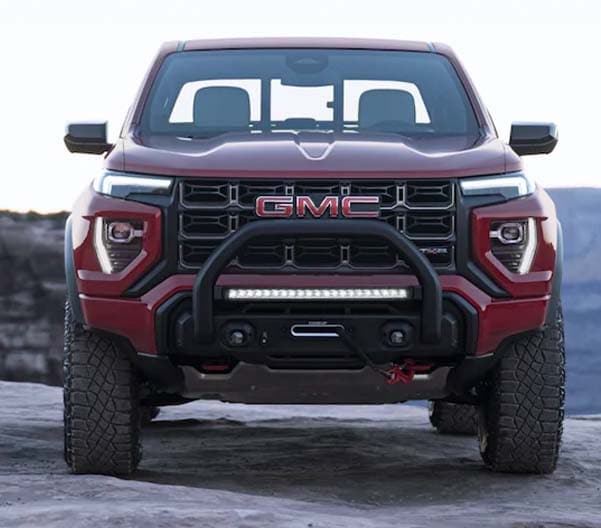 Exterior shot of a 2023 GMC Canyon on dirt with mountains in the background.