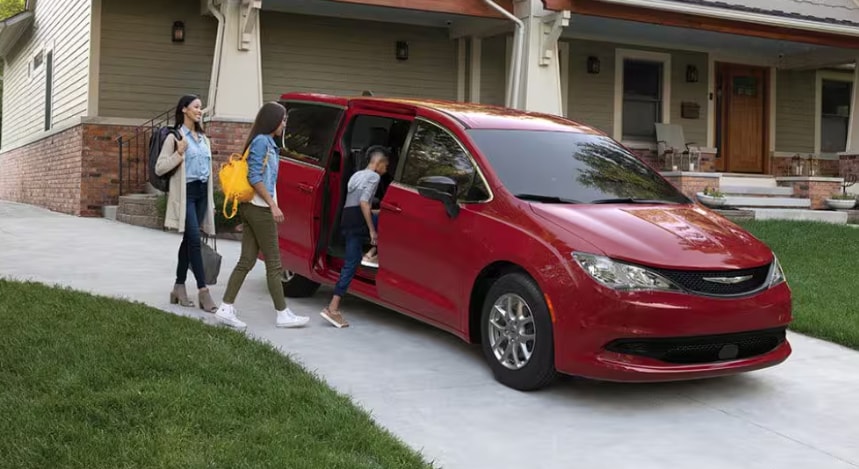Family entering a red 2026 Chrysler Voyager