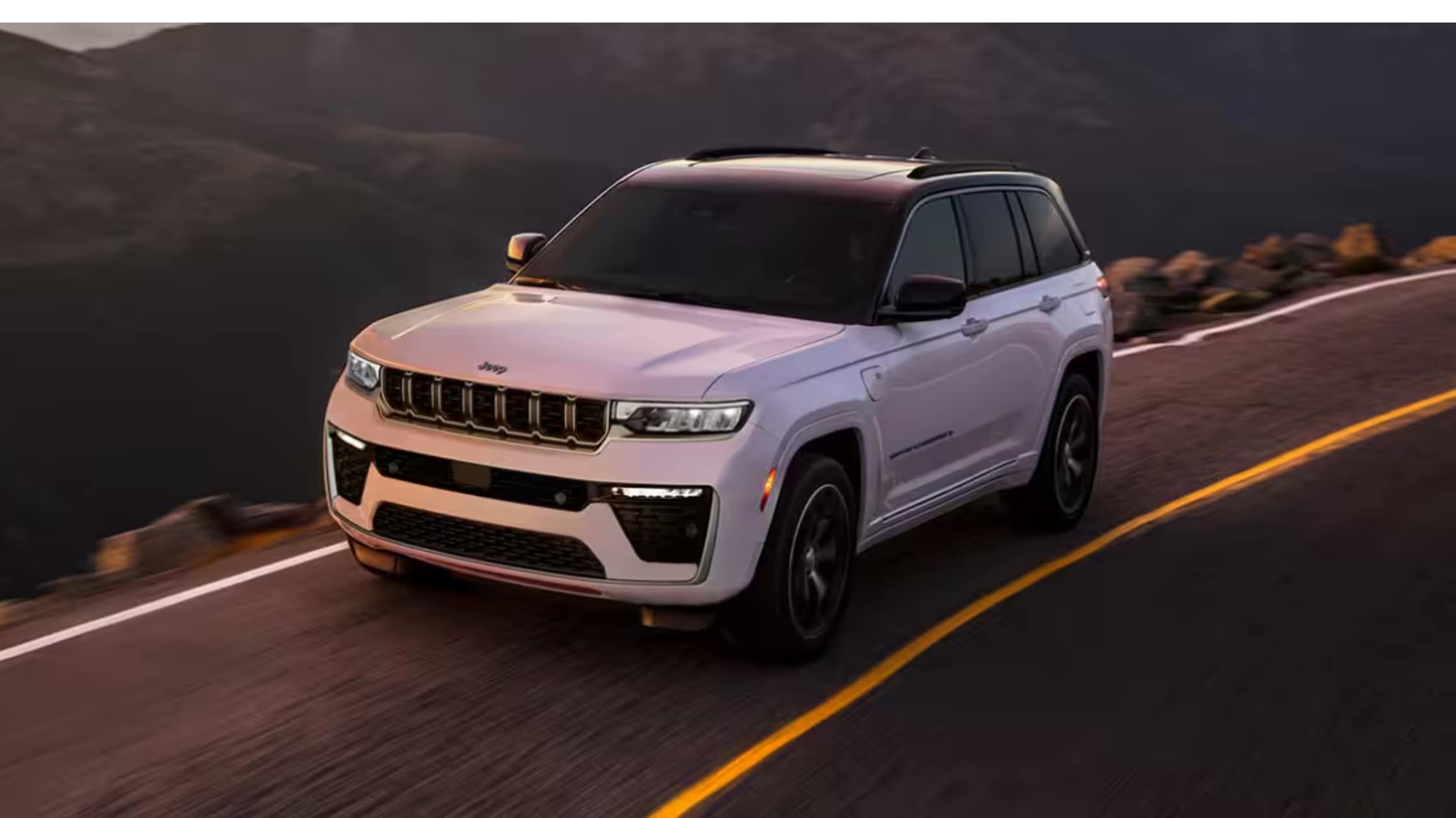 White Jeep Grand Cherokee driving fast down a mountain