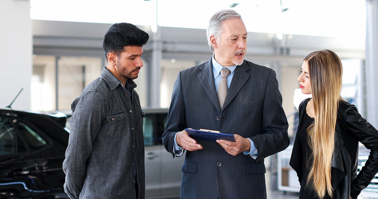 Customers speaking with salesperson at a Volkswagen dealership