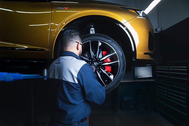 An Acura service technician removing a wheel from a vehicle