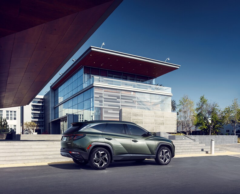 2025-Hyundai-TucsonHybrid-Limited-SUV-2.png green Hyundai Tucson Hybrid parked in front of a modern building