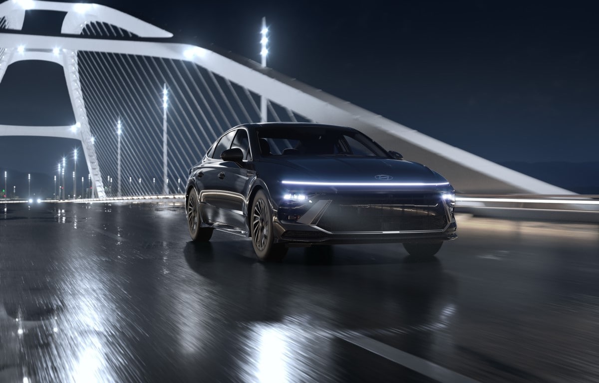 2024_Sonata_HEV_Limited_FWD_OnyxBlack_Black_360_Landscape_CityBridge.001.jpg dark grey Hyundai Sonata hybrid driving over a bridge on a dark and rainy night