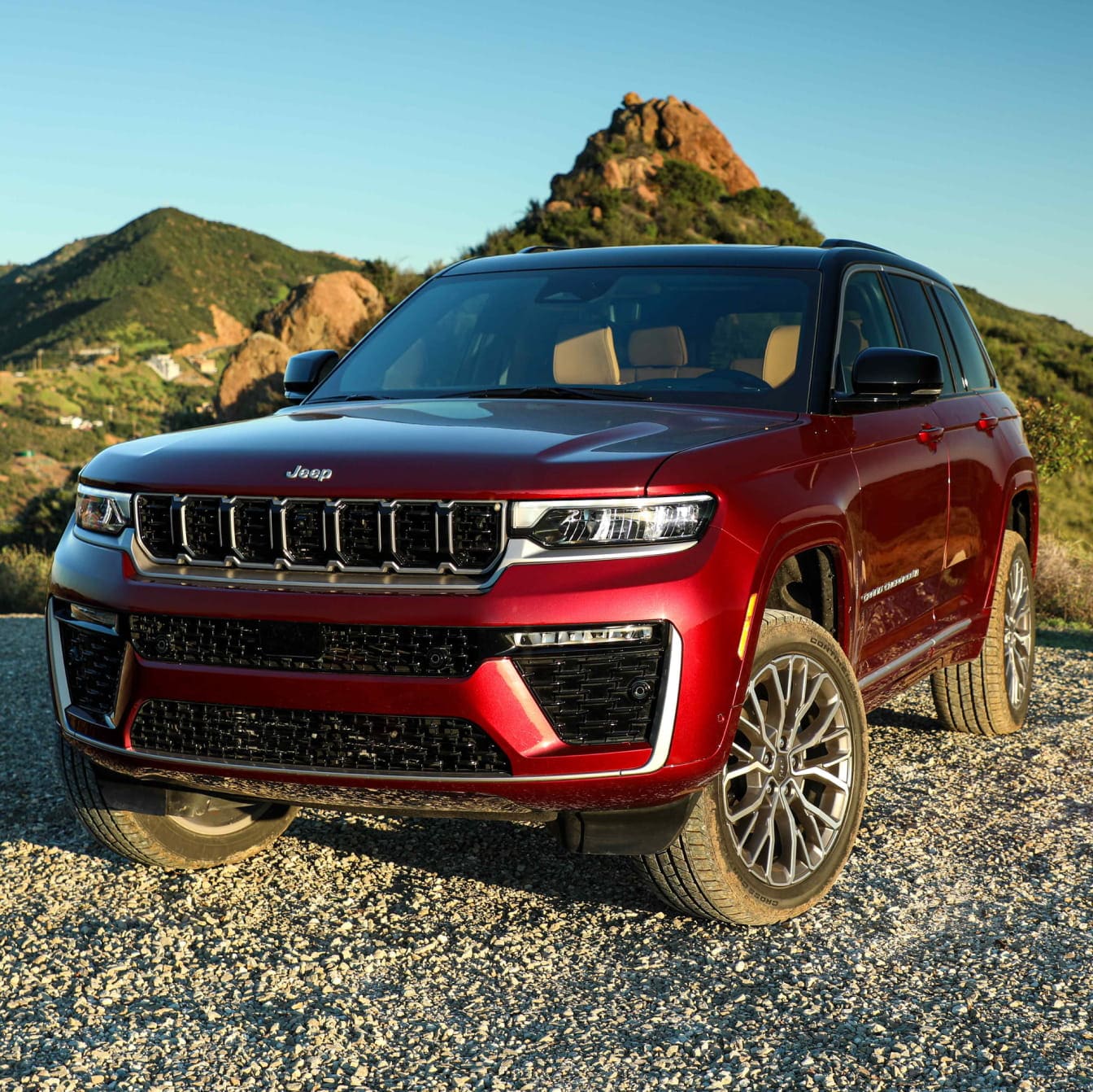 2026 Jeep Grand Cherokee parked on a gravel road with mountainous landscape in the background.