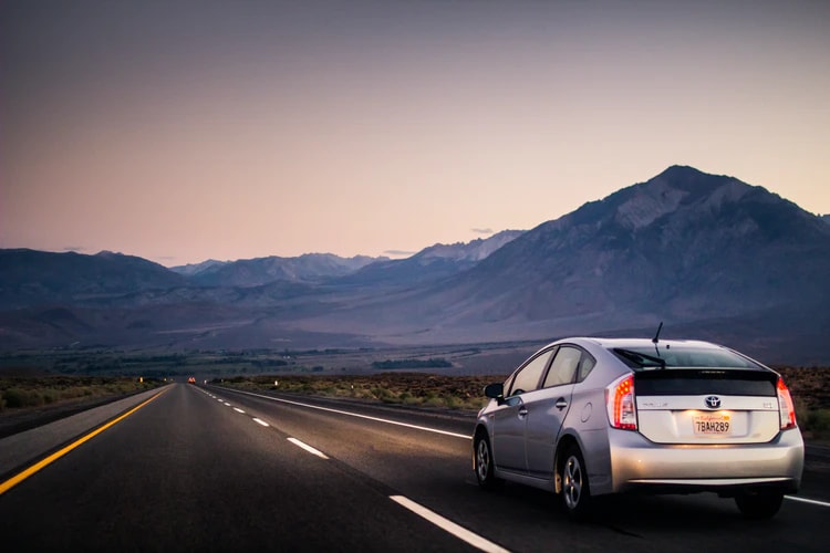 new toyota prius driving down mountainous highway at sunset
