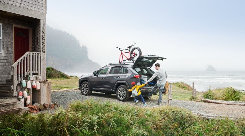Father and Son Playing Outside a 2021 Toyota RAV4 Parked Next to the Shore