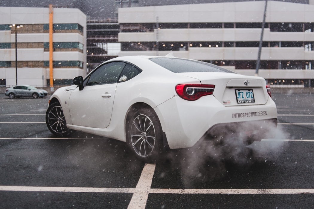 White Toyota Vehicle Outside of Snowy Parking Garage Spinning Out Due to Tire Pressure Issue