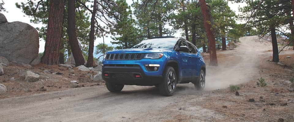 2019 Jeep Compass A blue 2019 Jeep Compass on a dirt trail in the forest