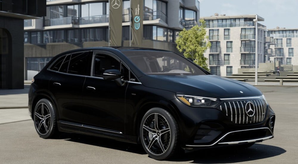 A black 2024 Mercedes-Benz EQE is shown parked near several buildings.