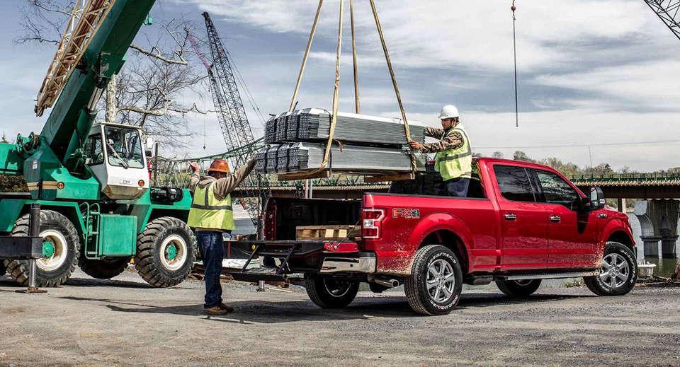 A red 2018 Ford F-150 being loaded up with beams