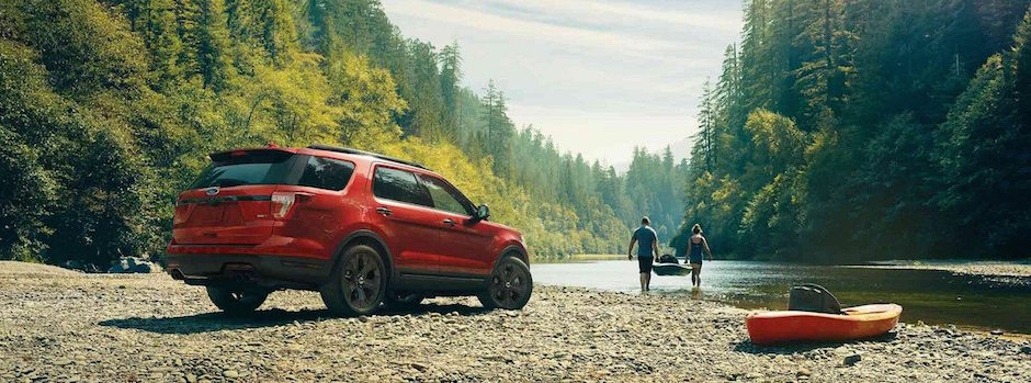A red Ford Explorer parked by a lake
