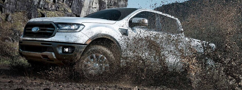 A white 2019 Ford Ranger driving through the mud