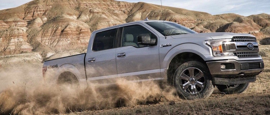 A grey 2018 Ford F0159 driving through the dirt