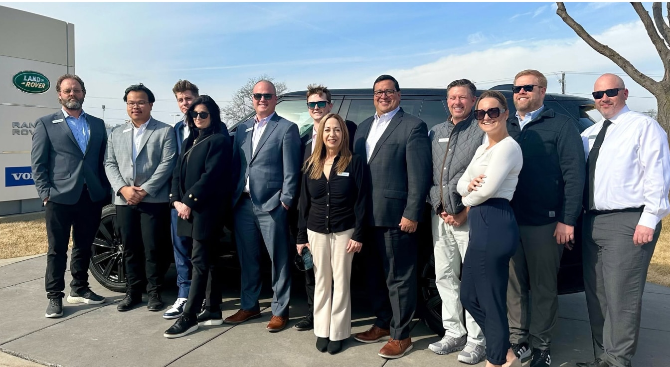 The Land Rover Des Moines team smiling while standing lined up outside the dealership.