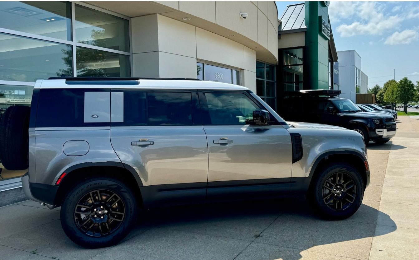 Exterior side view of a silver Land Rover parked outside the Land Rover Des Moines dealership.
