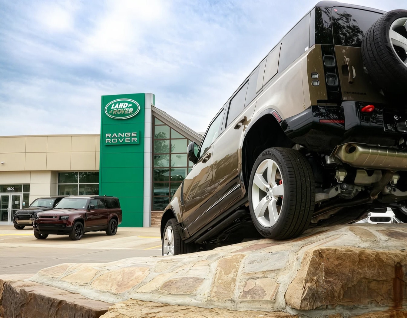 Outdoor view of Land Rover Des Moines with a rear perspective of a Land Rover on a rock feature.