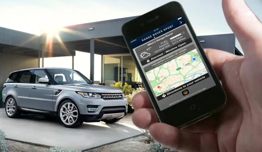 A close-up of a smartphone with Land Rover InControl on the screen with a Land Rover vehilce in the background