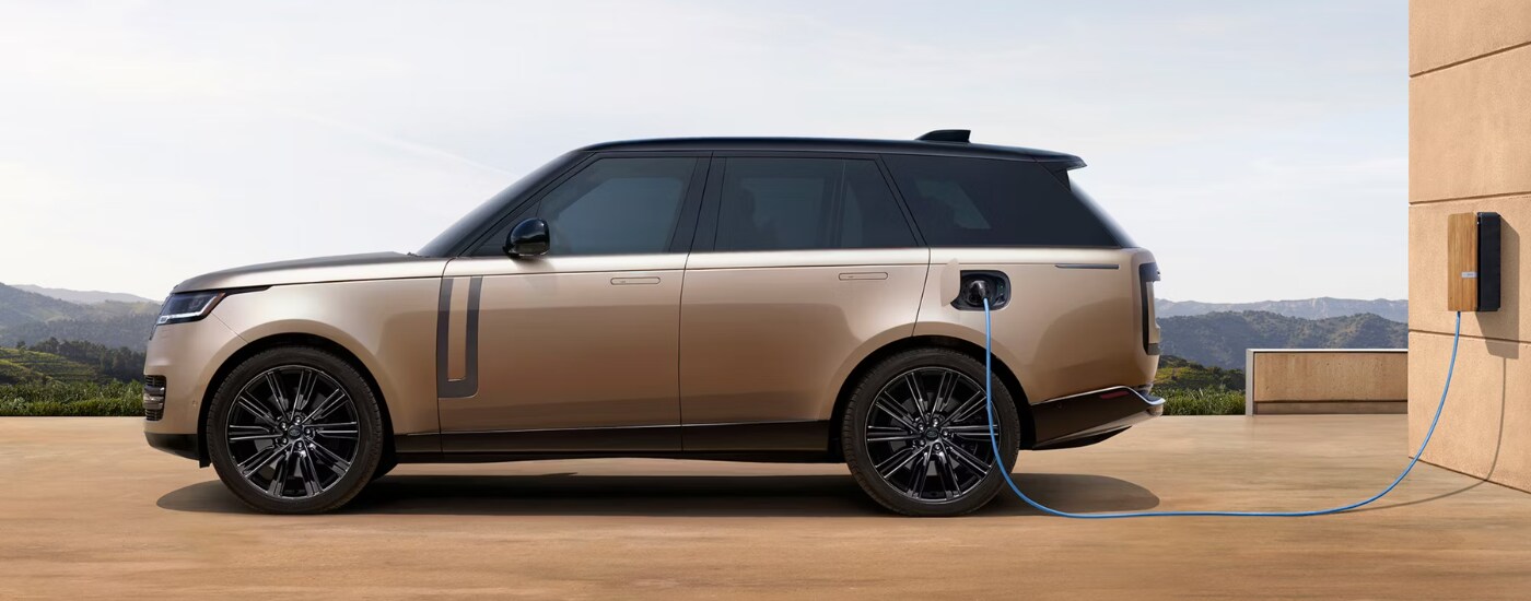 Side profile of a beige 2026 Range Rover charging in a driveway