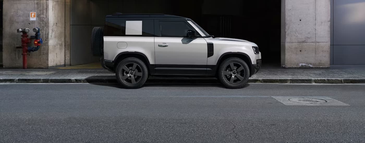 Side of a white 2026 Land Rover Defender parked by a curb.